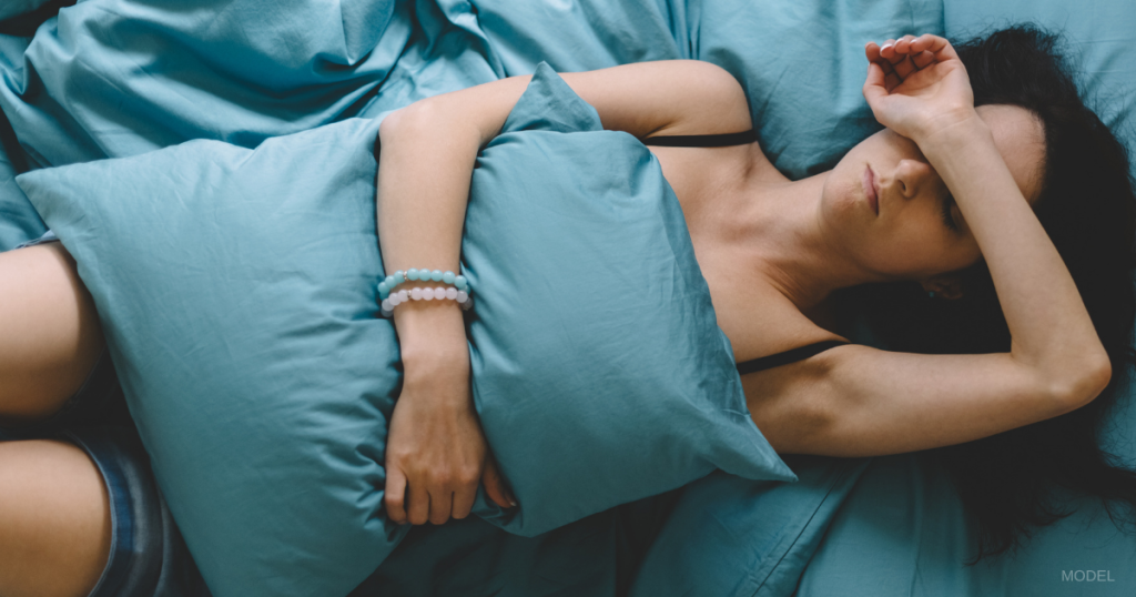 Woman lying in bed with a cold before plastic surgery appointment