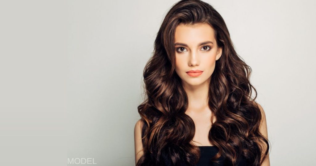 Brunette woman with long hair against gray wall (MODEL)